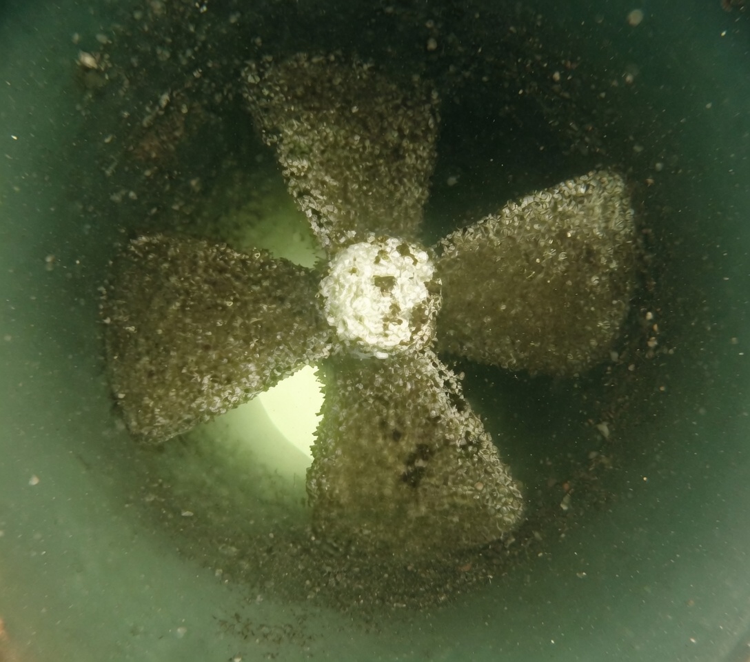 Boat propeller covered in barnacles and marine growth before professional underwater cleaning